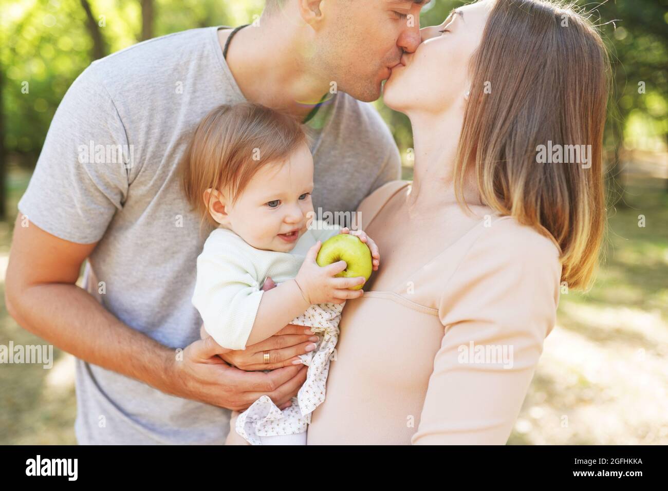 Glückliche Familie im Park. Die Lichter einer Sonne. Mama, Papa und Baby gehen bei Sonnenuntergang glücklich. Das Konzept einer glücklichen Familie Stockfoto