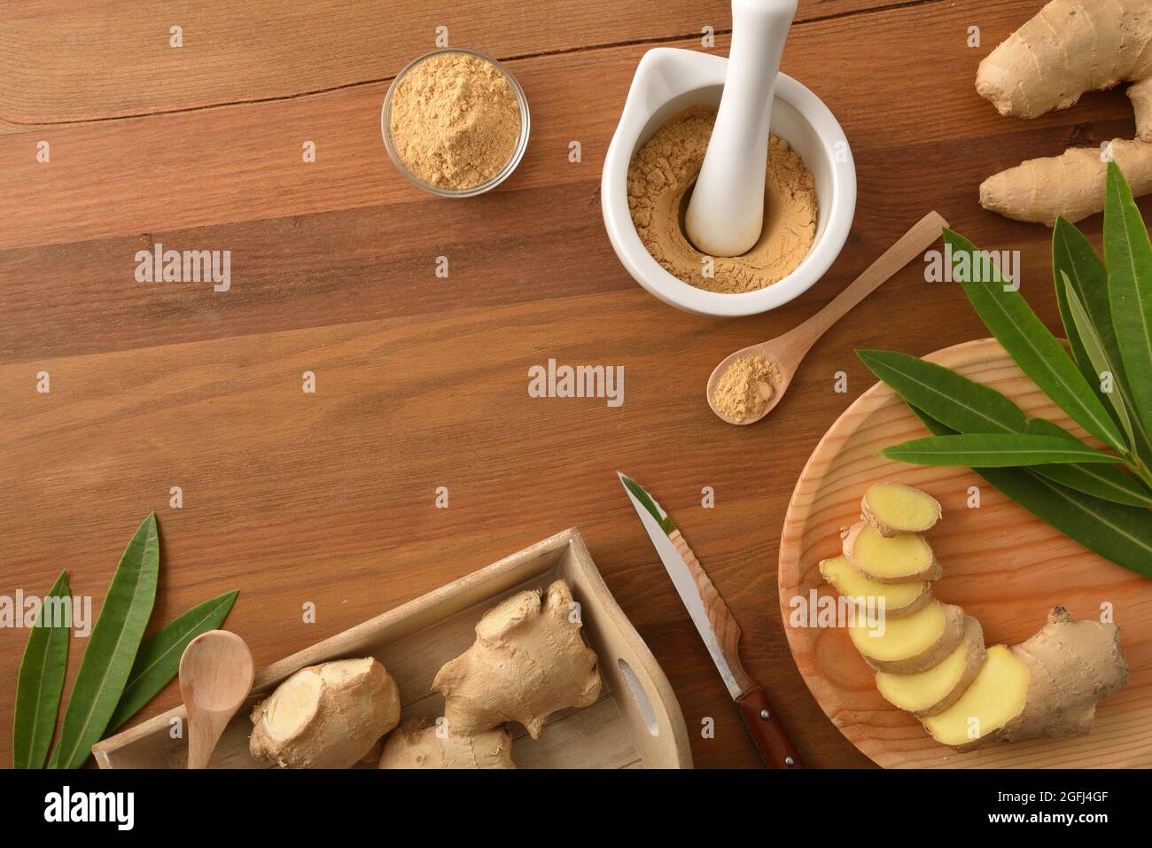Ingwerpulver-Zubereitung für heilende und kulinarische Zwecke mit Ingwerwurzel in Portionen auf Holztisch geschnitten. Draufsicht. Stockfoto