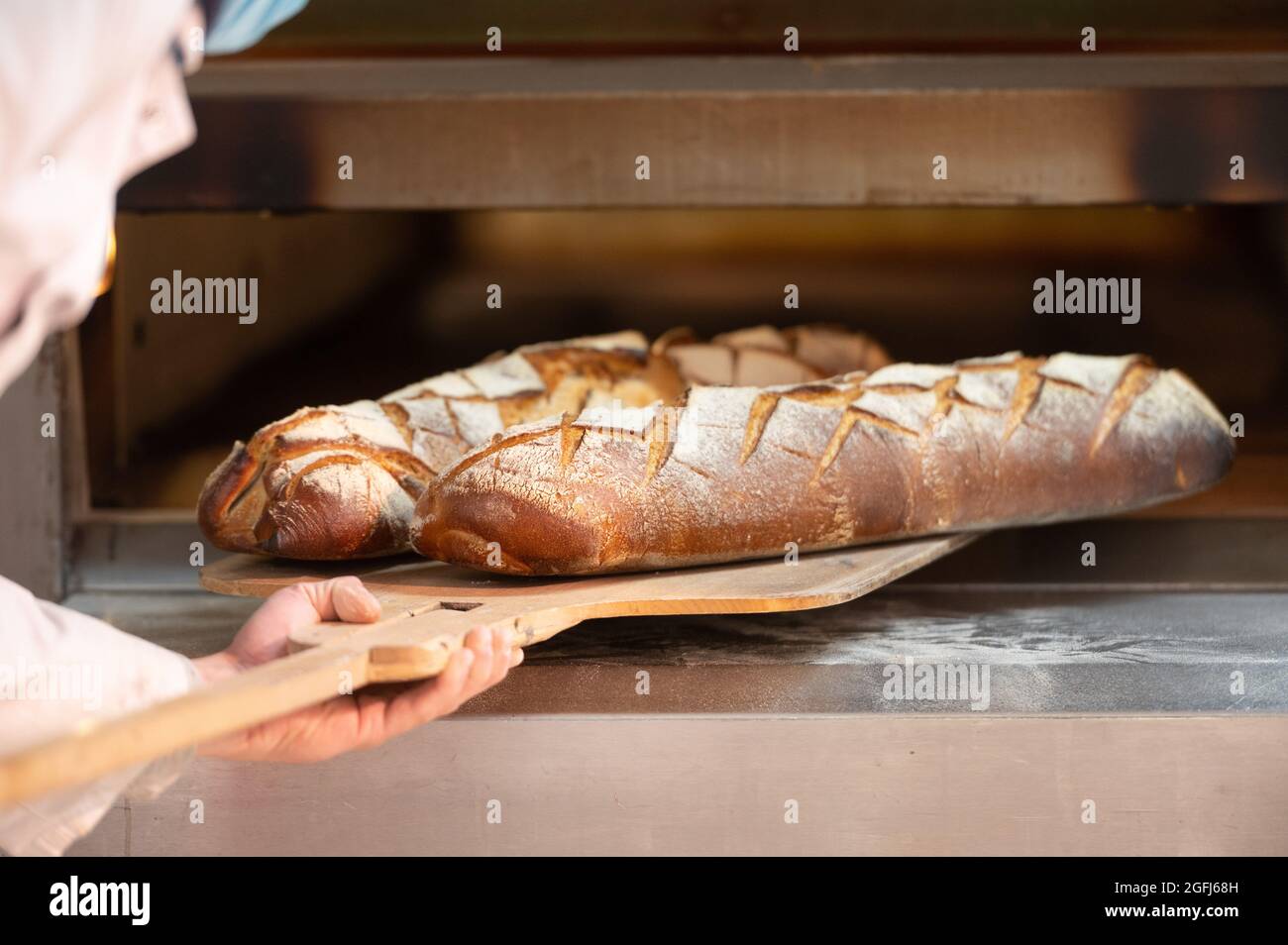 Super U Supermarkt : jemand, der Brot Baker nimmt Bauernbrot aus dem Ofen Stockfoto