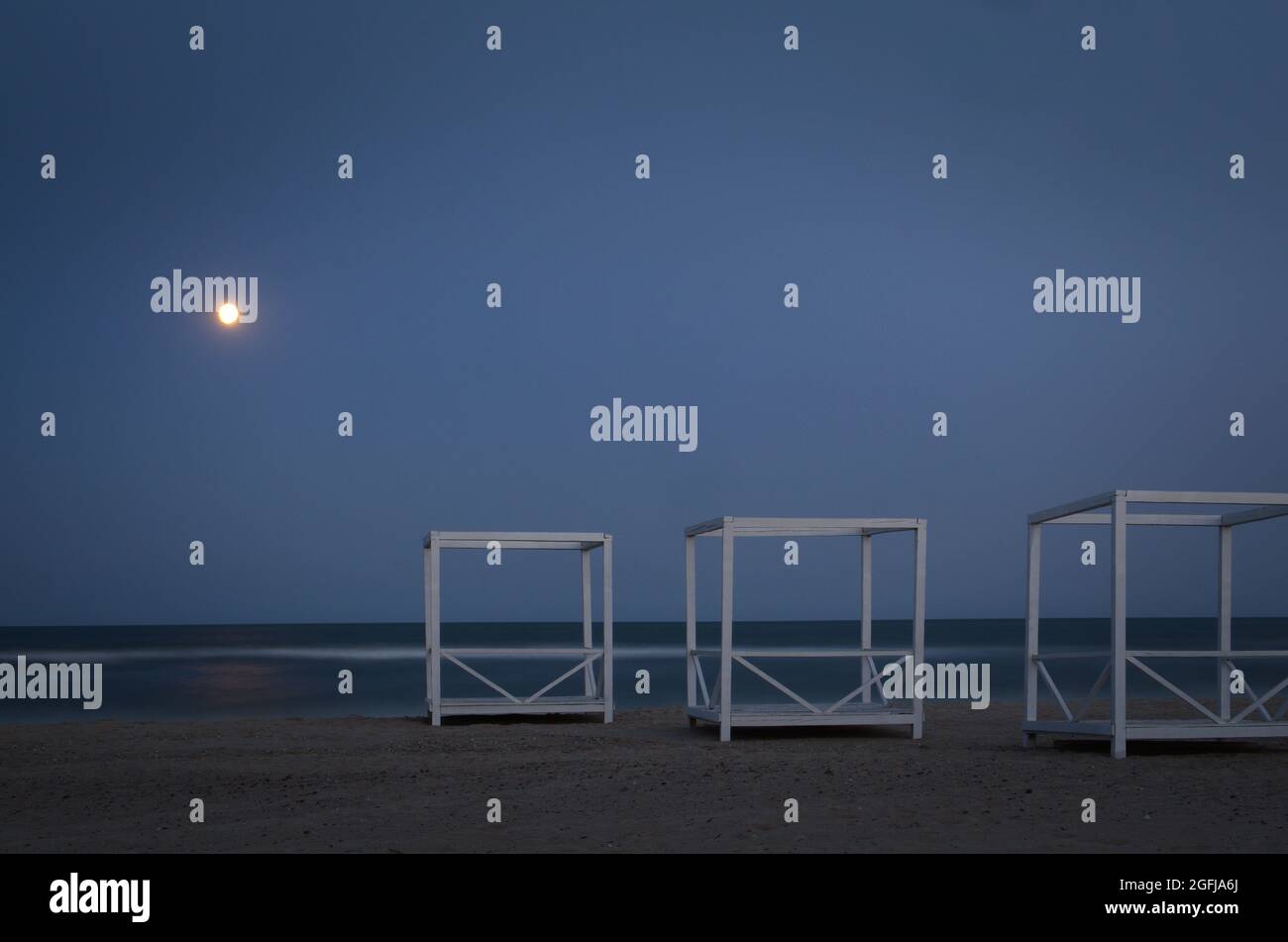 Drei hölzerne Pavillons an der Küste und Mond bei Nacht Stockfoto