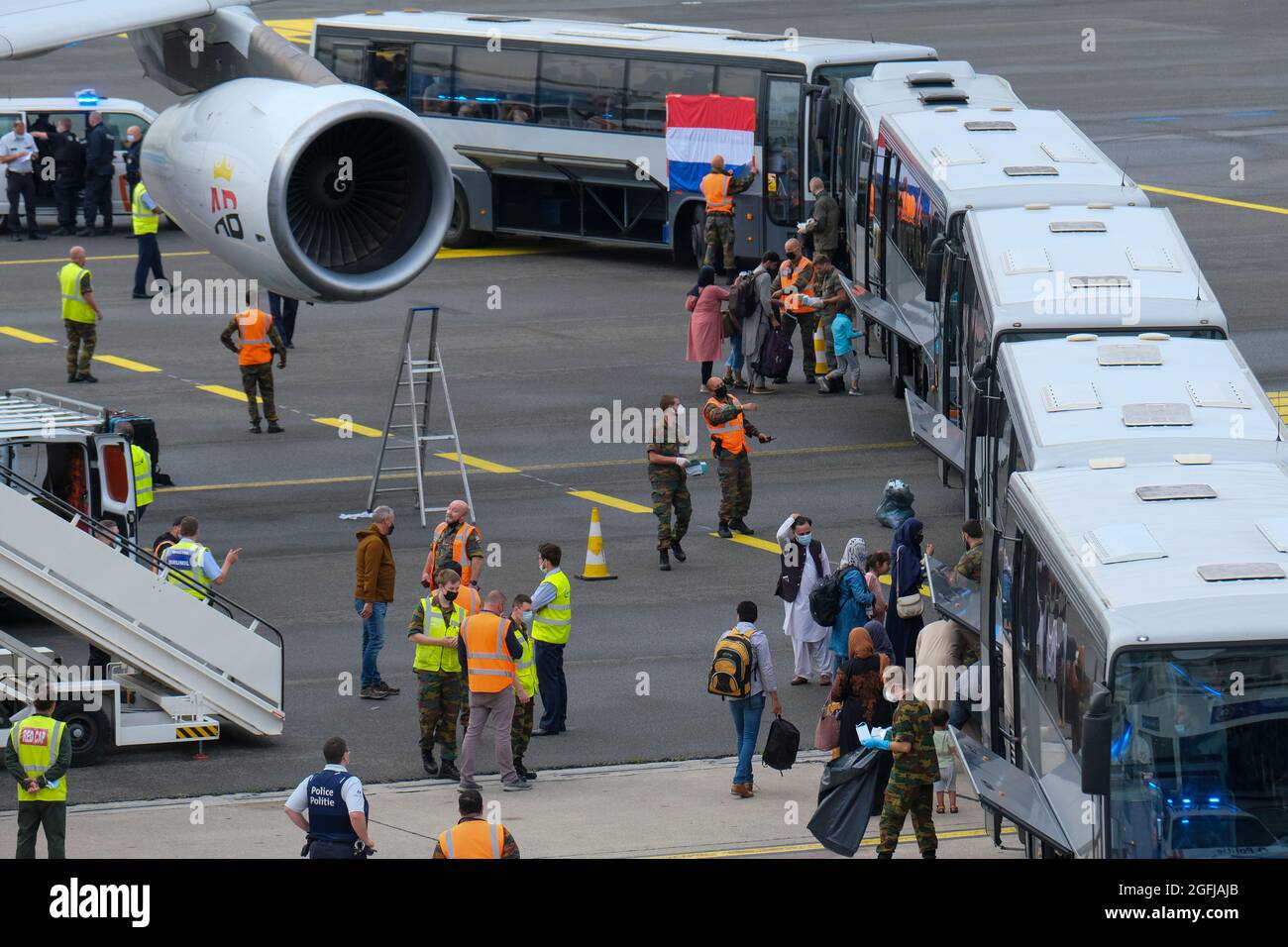 Die Abbildung zeigt, wie Menschen bei der Ankunft eines von Air Belgium gecharterten Airbus A340, der evakuierte Menschen aus Afghanistan befördert, in Busse steigen Stockfoto