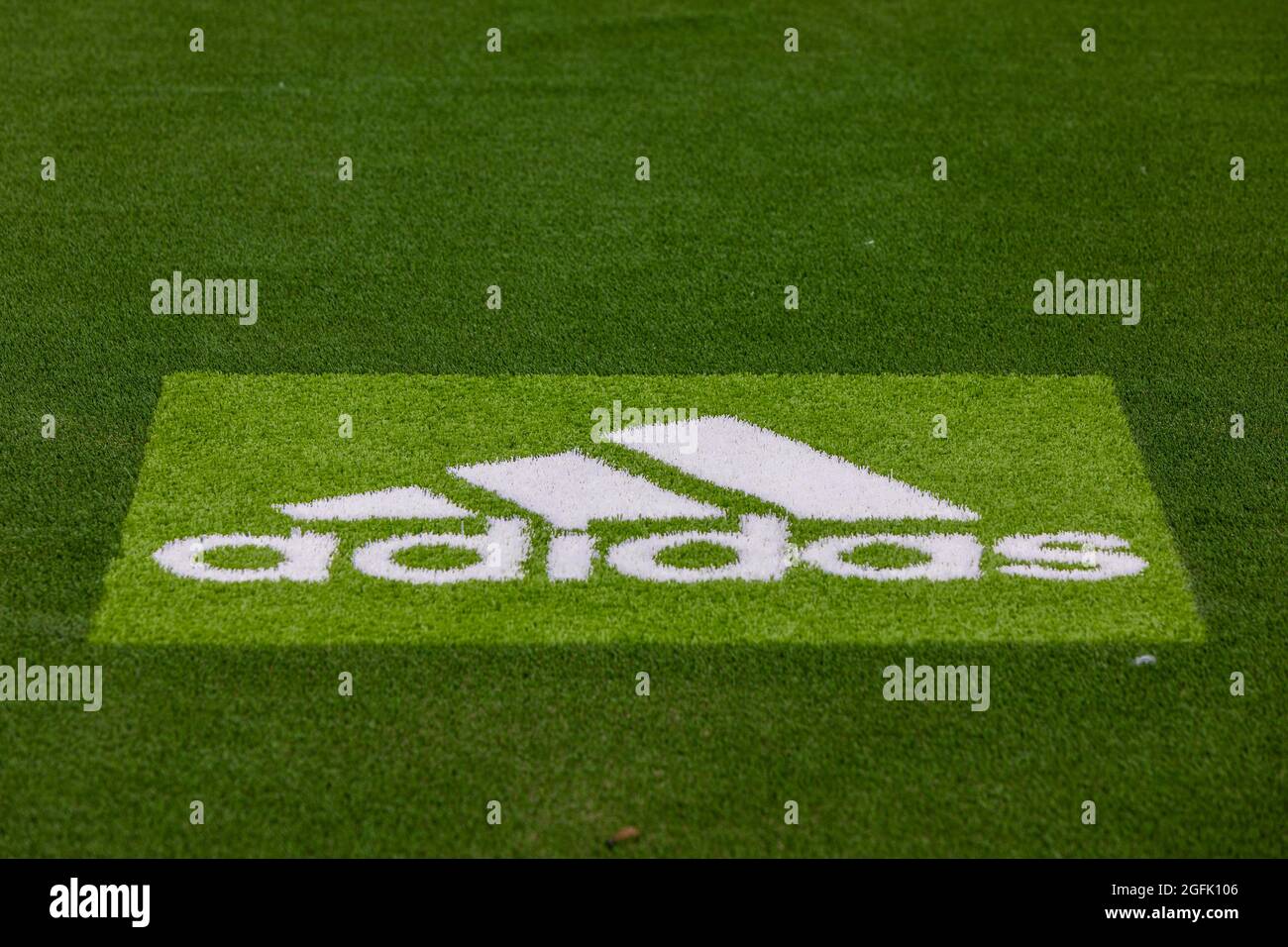 Logo des Sportartikelherstellers Adidas auf dem Kunstrasen eines Fußballfeldes, weißes Logo auf grünem Hintergrund Stockfoto