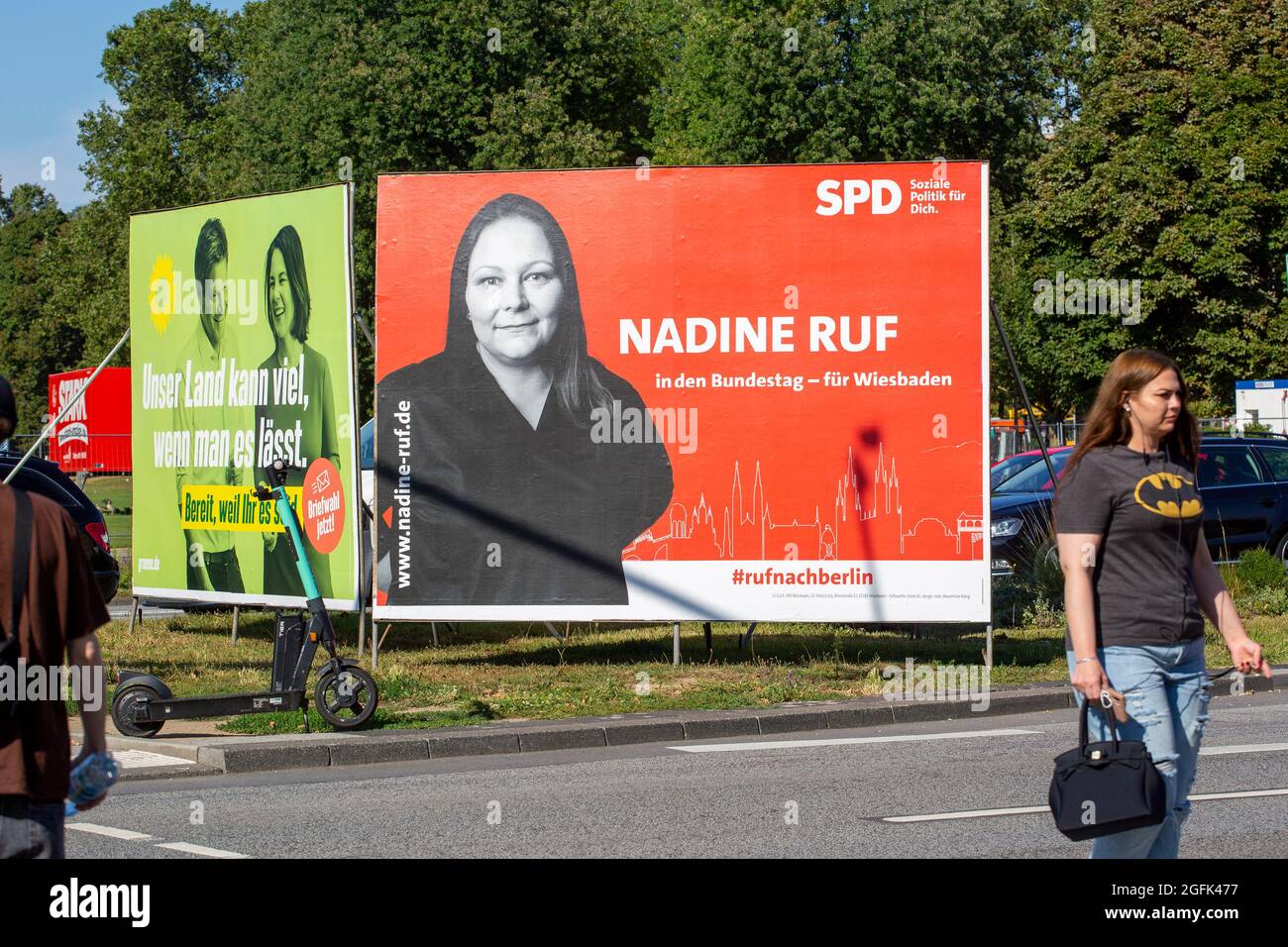 Wiesbaden, Deutschland - 25. August 2021: Wahlkampfplakate der Partei DIE GRÜNEN und der Sozialdemokratischen Partei (SPD) in der Innenstadt von Wiesbaden, Hessen. Deutschland steht am 26. September vor Bundestagswahlen. Einige Verkehrsteilnehmer im Hintergrund Stockfoto