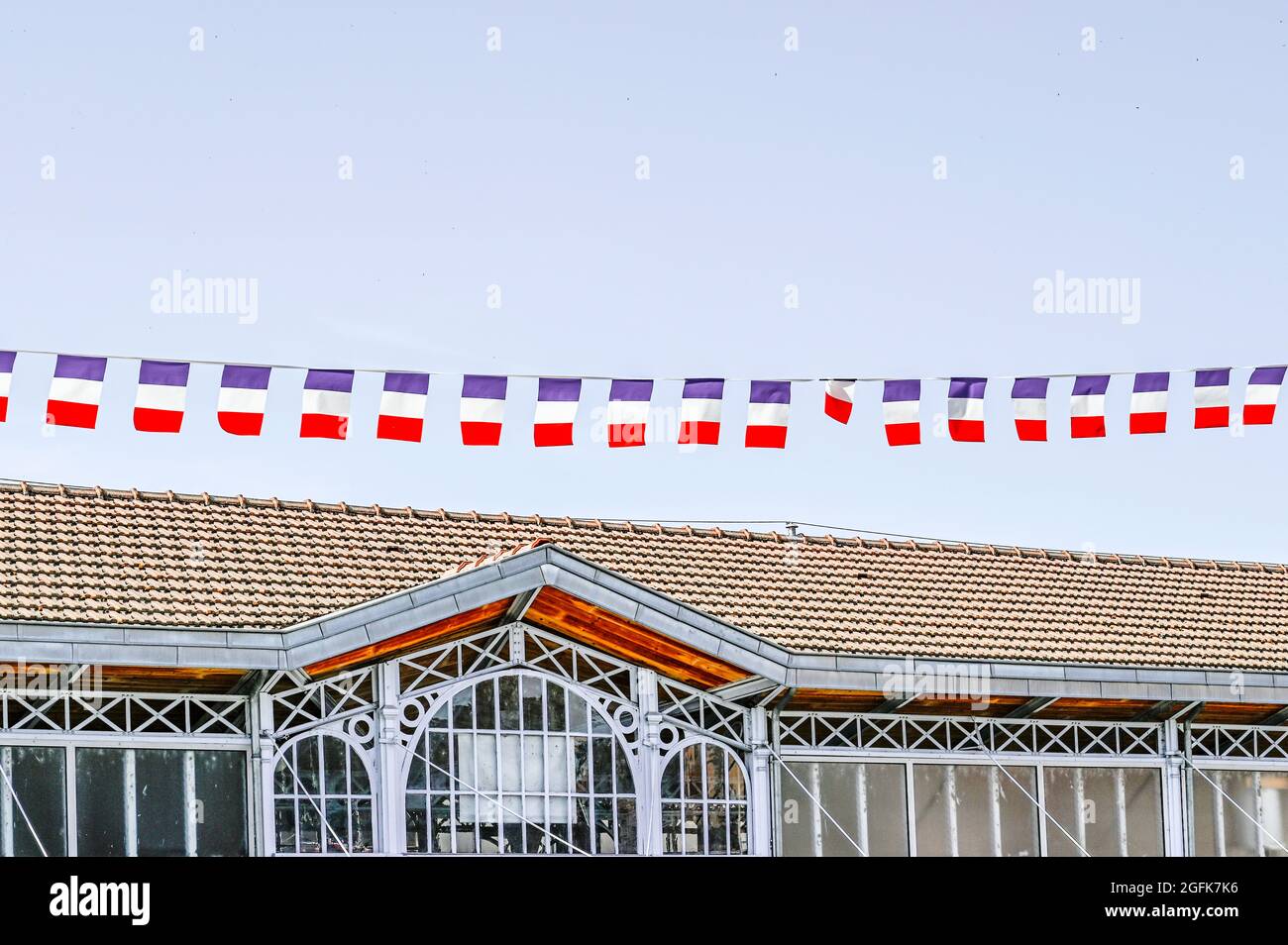 Französische Flaggen winken im Wind über dem Dach der Markthalle von Saint-Cyprien anlässlich des französischen Nationalfeiertags, dem 14. Juli. Stockfoto