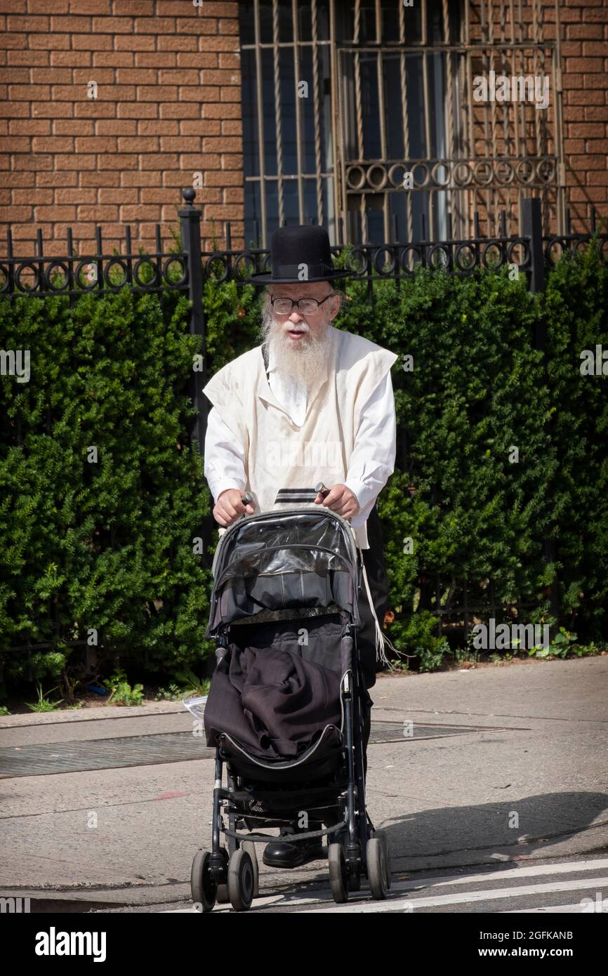 Ein chassidischer Großvater schiebt einen leeren Kinderwagen auf die Bedford Avenue in Williamsburg, Brooklyn, New York. Stockfoto
