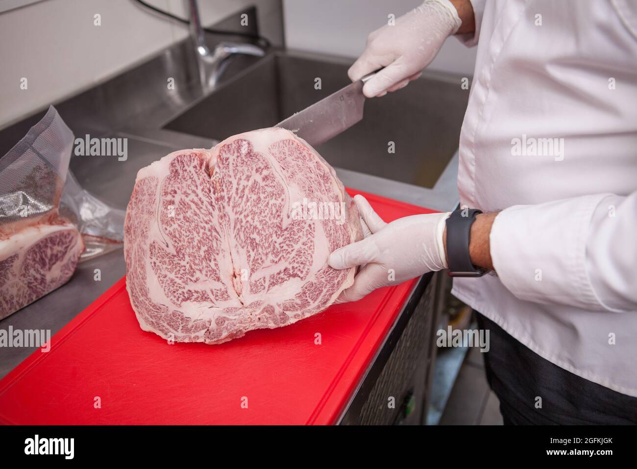 Unkenntlich, dass der Koch in der Küche marmortes Rindfleisch schneide Stockfoto
