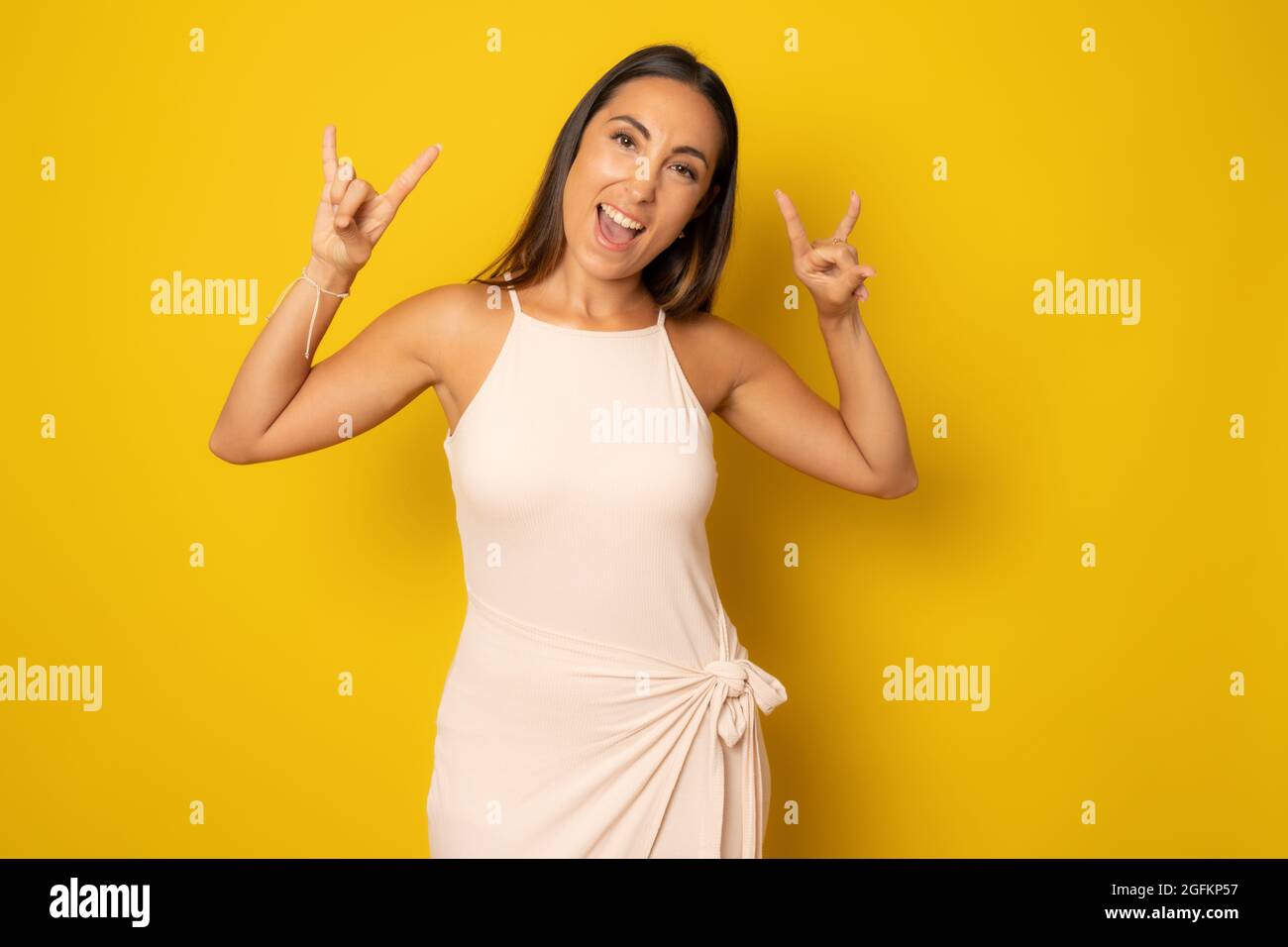 Junge schöne Frau casual weißes Kleid über isolierten Hintergrund schreiend mit verrückten Ausdruck Rock-Symbol mit Händen nach oben tun. Musikstar. Schwere CO Stockfoto