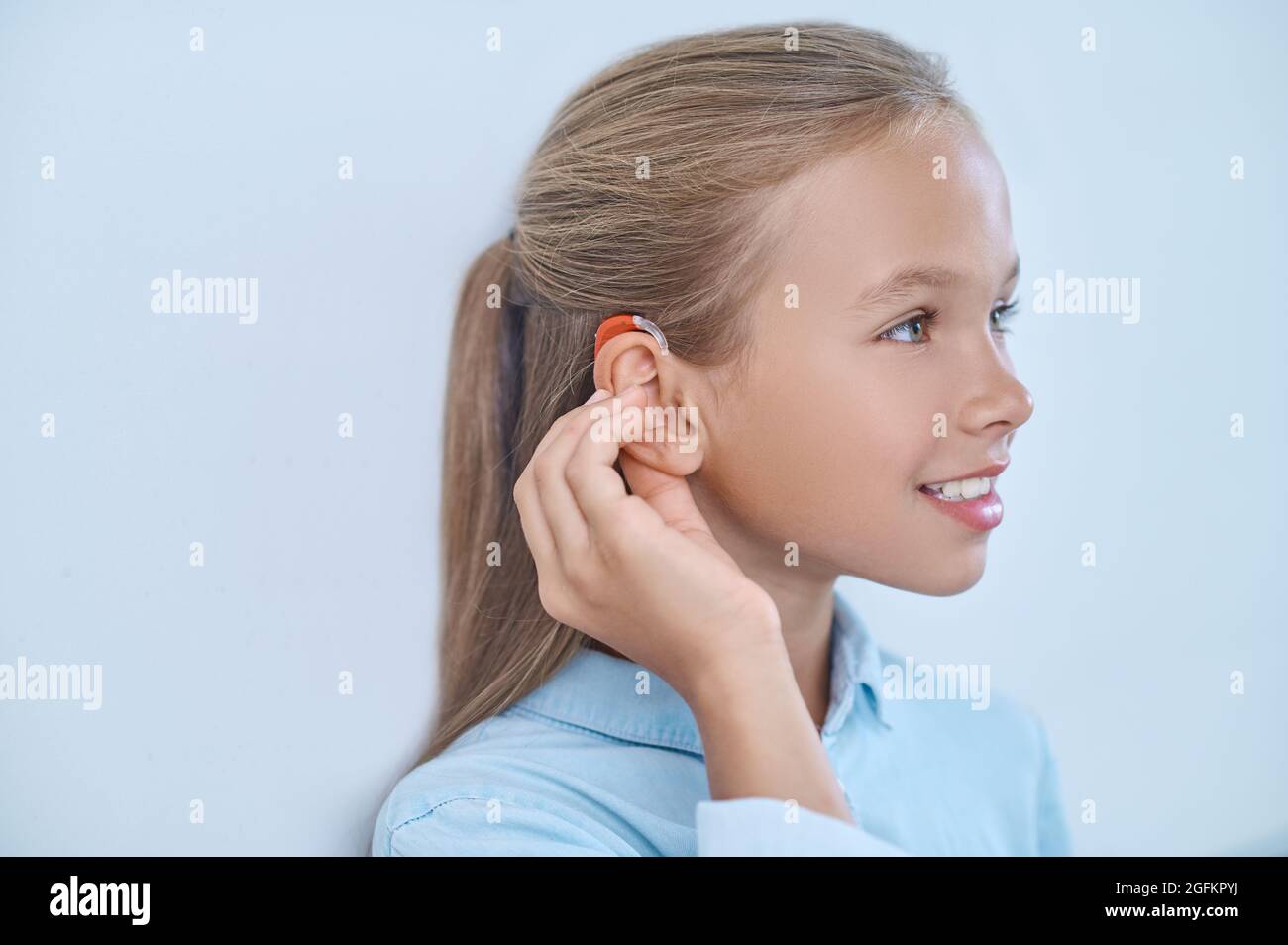 Profil eines Mädchens, das das Ohr mit einem Hörgerät berührt Stockfoto