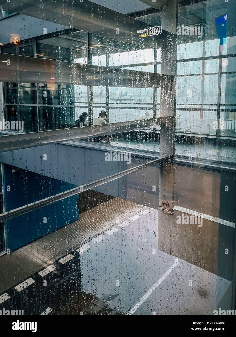 Einige Flughafenmitarbeiter sitzen auf einem leeren Flughafen hinter einer Glaswand Stockfoto