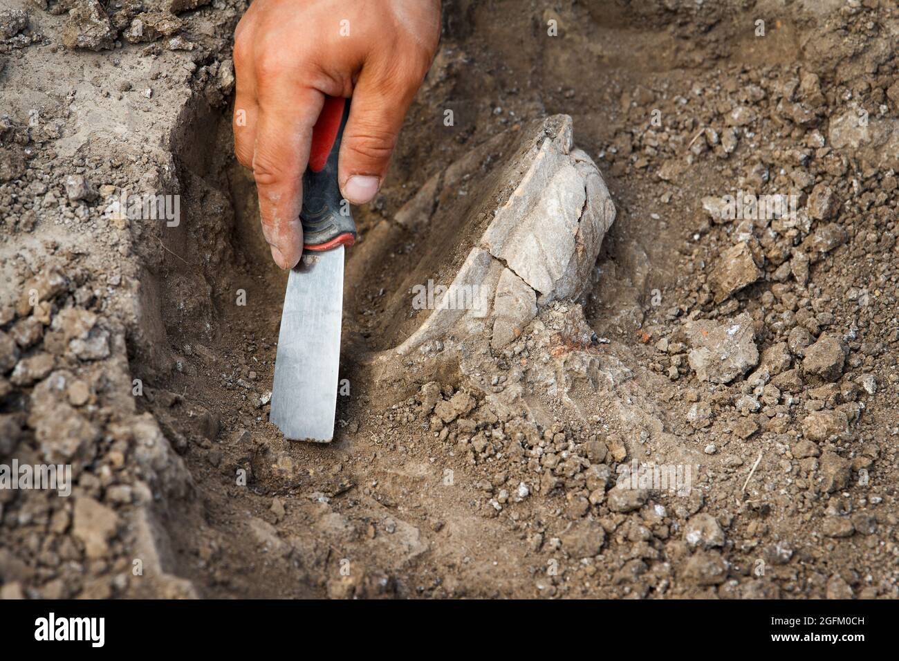 Archäologische Ausgrabungen, Archäologen arbeiten, graben ein altes Tonartefakt mit speziellen Werkzeugen im Boden Stockfoto