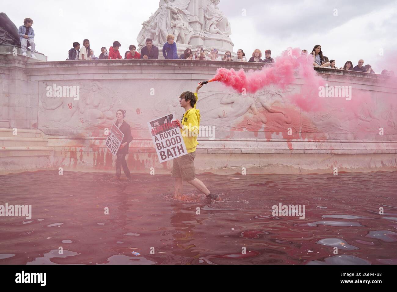 Während eines Protestes vor dem Buckingham Palace in London lassen Demonstranten des Extinction Rebellion im Brunnen des Queen Victoria Memorial, den sie mit roter Farbe überzogen haben, Leuchtraketen los. Bilddatum: Donnerstag, 26. August 2021. Stockfoto
