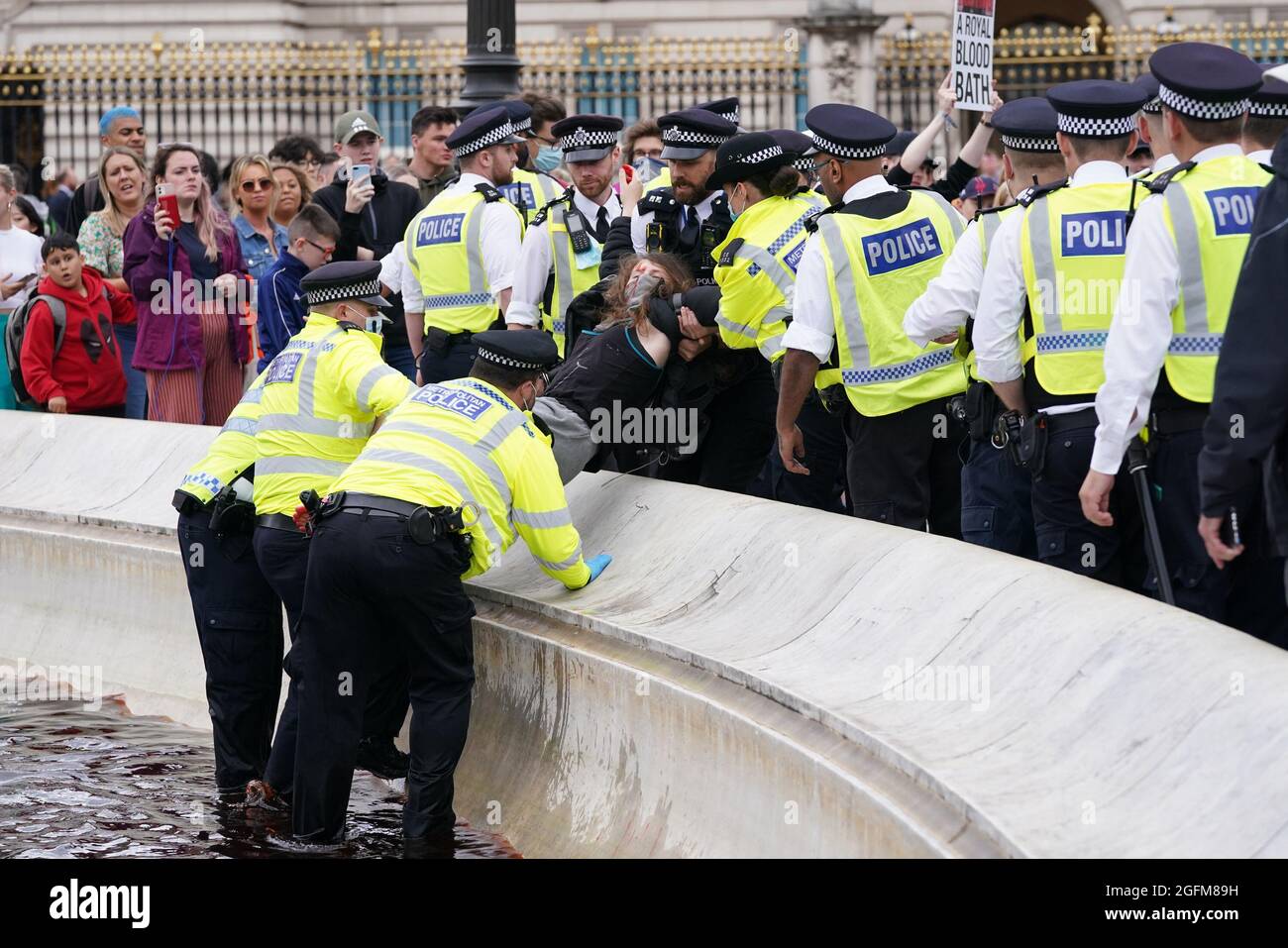 Polizeibeamte entfernen Demonstranten aus dem Brunnen am Queen Victoria Memorial, den sie mit roter Farbe überzogen haben, während eines Protestes vor dem Buckingham Palace, London, zum Aussterben der Rebellion. Bilddatum: Donnerstag, 26. August 2021. Stockfoto