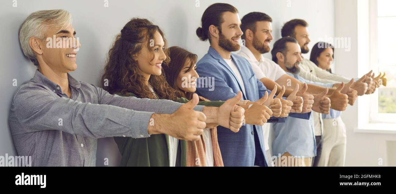 Gruppe von glücklichen, selbstbewussten und erfolgreichen Geschäftsleuten, die wie eine Geste Daumen nach oben tun Stockfoto