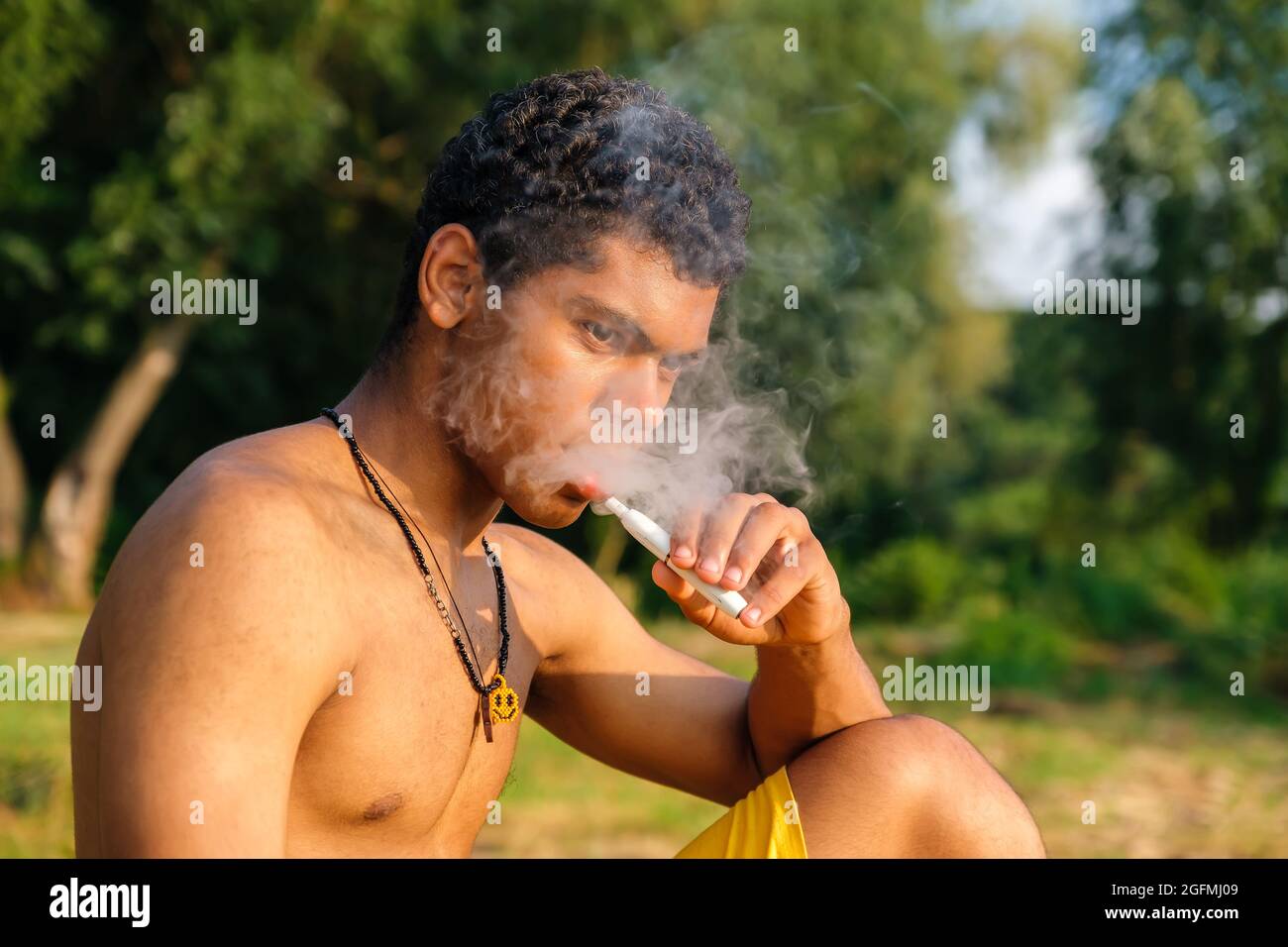 Afroamerikanischer junger Mann, der E-Zigarette mit E-Liquid verdampft Stockfoto