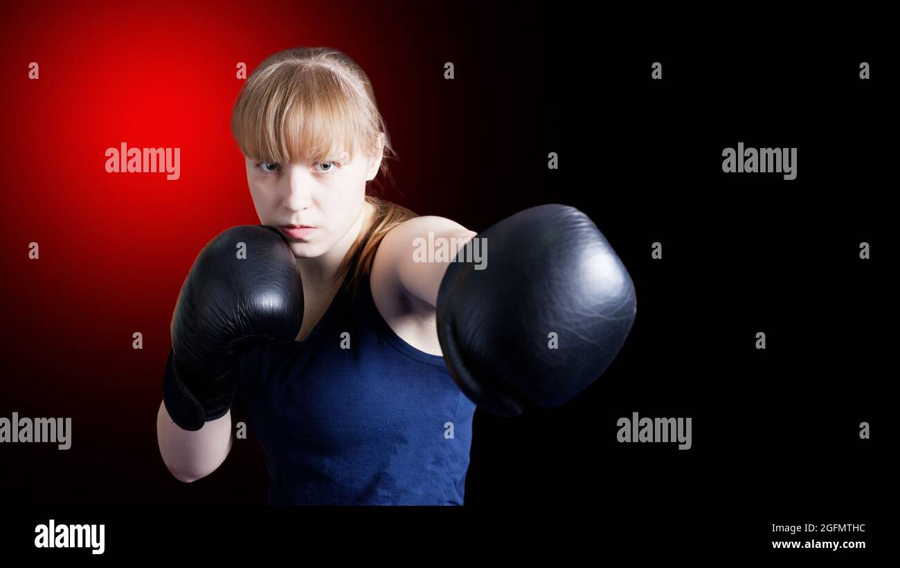 Sportliche Mädchen tun Boxen Übungen, so dass direkt getroffen isoliert auf schwarzem Hintergrund mit rotem Fleck. Copyspace. Stockfoto