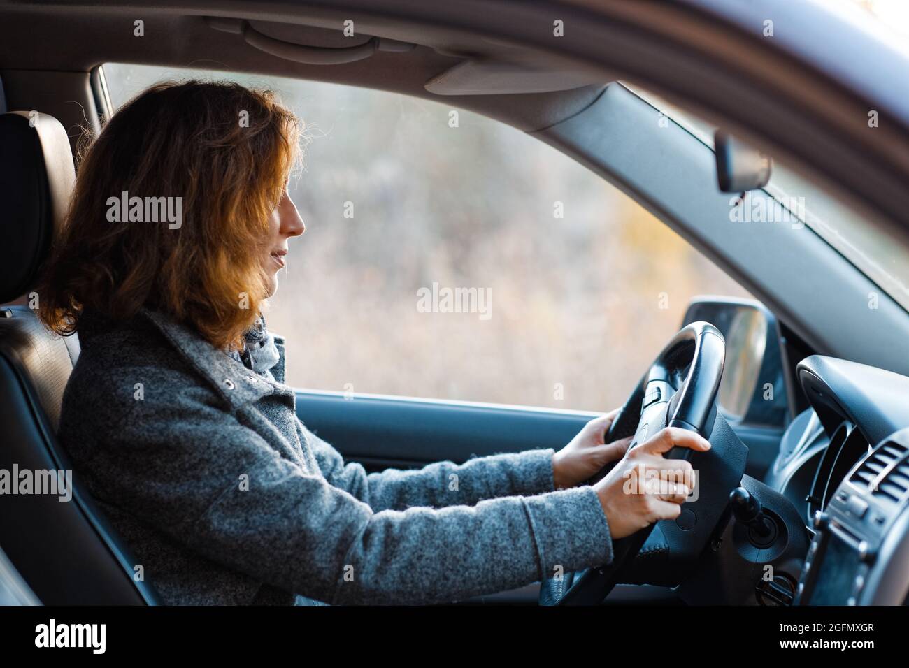 Porträt einer Rotschopf-Frau, die ein Auto fährt und geradeaus blickt. Stockfoto
