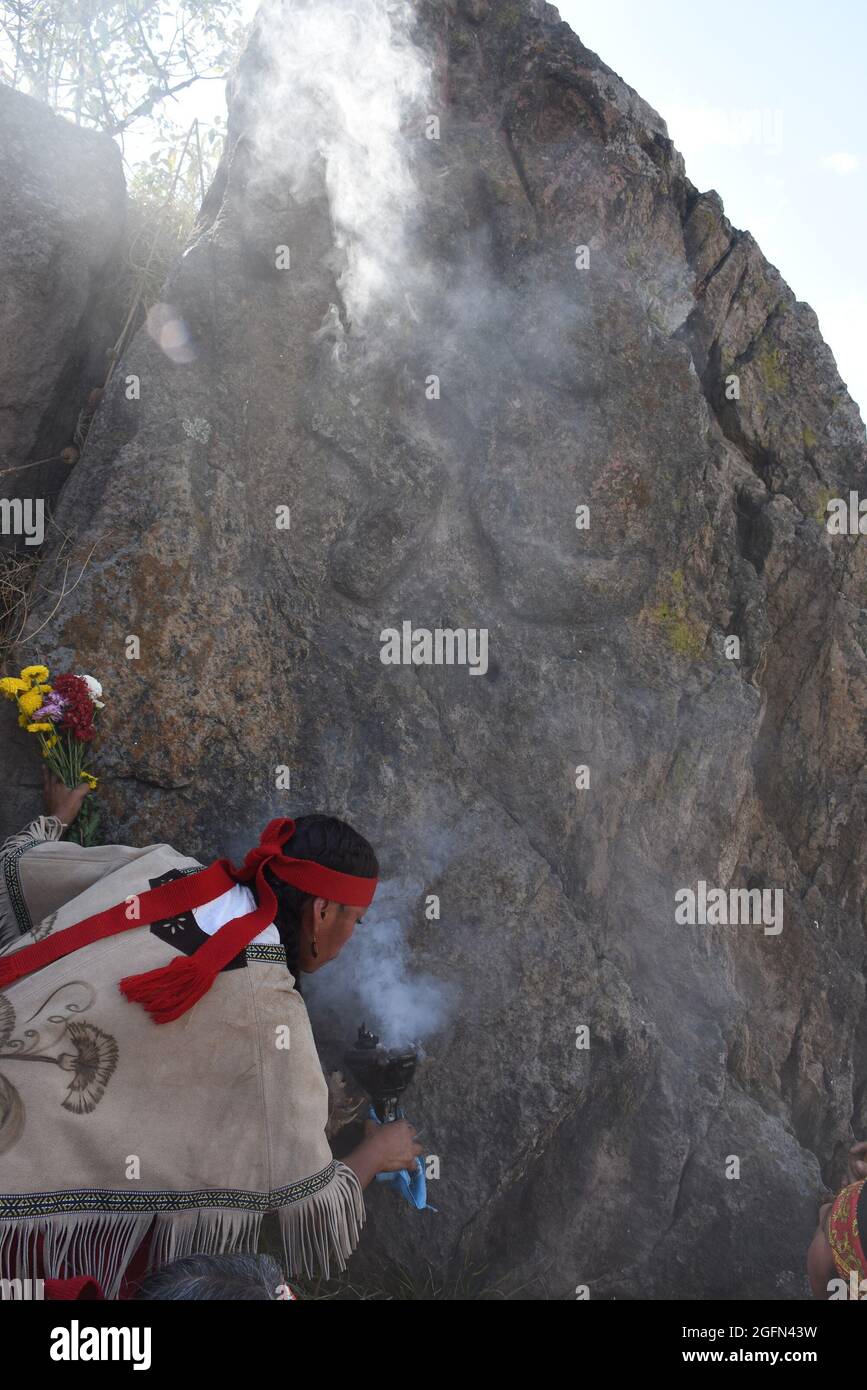 Curanderas – traditionelle Heiler oder Schamanen – führen ein Ritual vor einem Felsblock mit einer Schnitzerei von Xipe Totec, dem aztekischen gott der Landwirtschaft, durch. Stockfoto