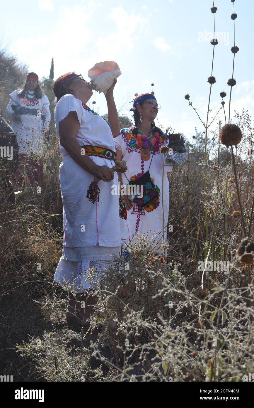 Curanderas – traditionelle Heiler oder Schamanen – führen ein Ritual vor einem Felsblock mit einer Schnitzerei von Xipe Totec, dem aztekischen gott der Landwirtschaft, durch. Stockfoto