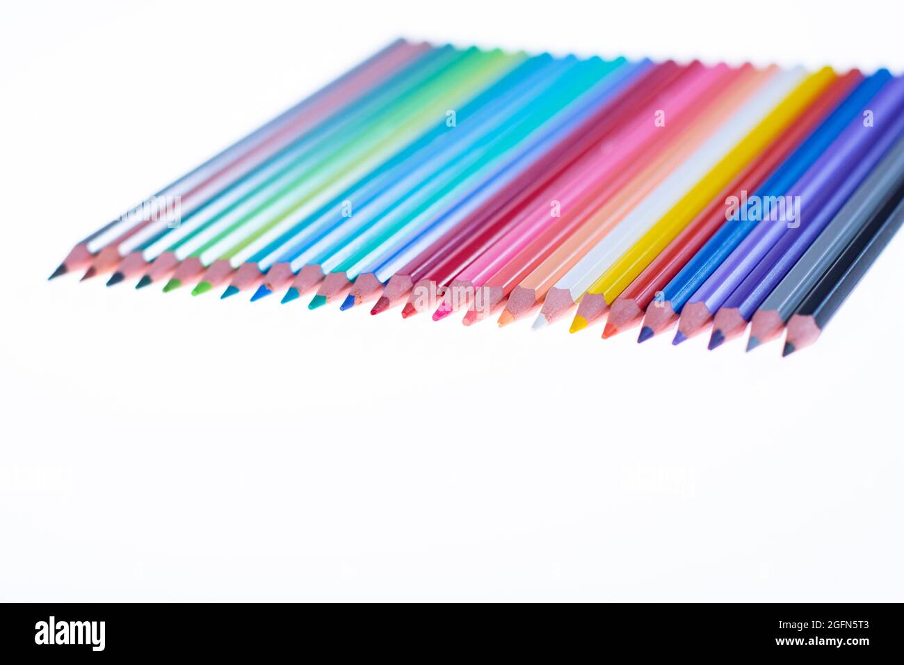24 bunte Buntstifte auf weißem Hintergrund, ordentlich angeordnet und geschärft. Hallo Schule Stockfoto