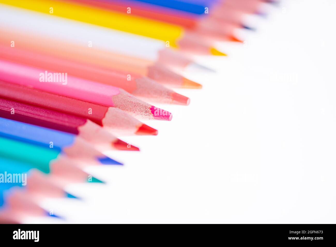 24 bunte Buntstifte auf weißem Hintergrund, ordentlich angeordnet und geschärft. Hallo Schule Stockfoto