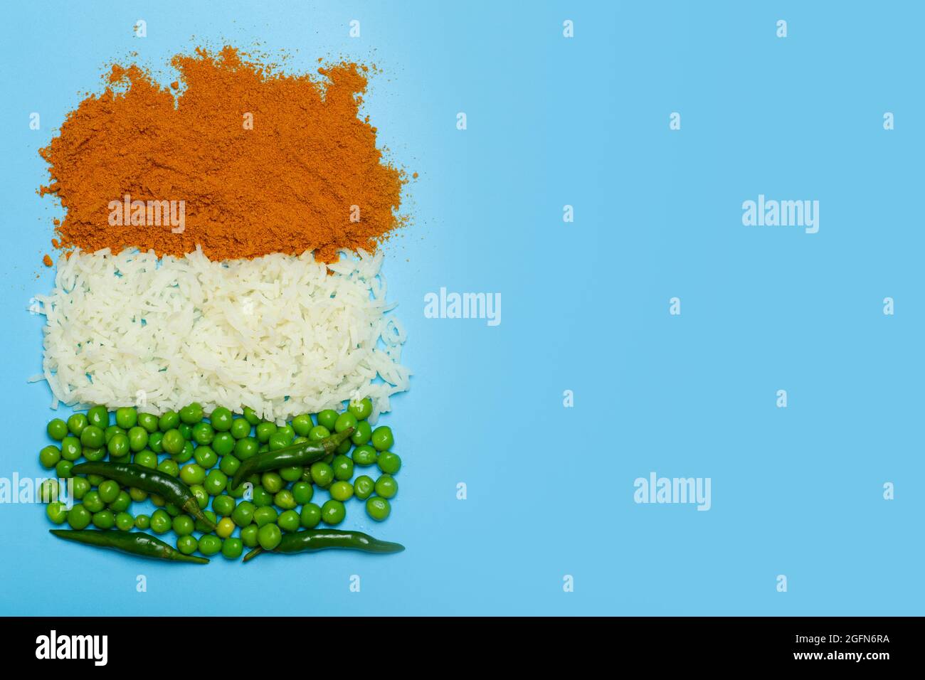 Indische Flagge aus Lebensmittelhintergrund. Basmati-Reis, Paprika, grüne Erbsen und Chilischoten in den Farben der indischen Flagge auf blauem Hintergrund. Hochwertige Fotos Stockfoto