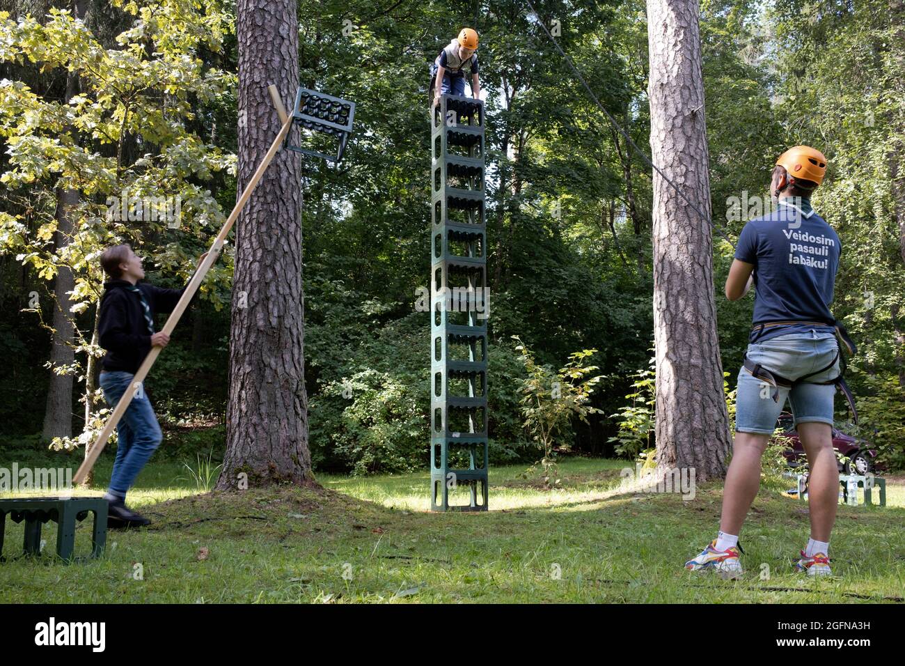Kiste klettern, ein Junge steht auf dem Stapel, Team auf dem Boden hilft, hält ihn sicher, führt Kisten, Ogre Stadt, Lettland Stockfoto