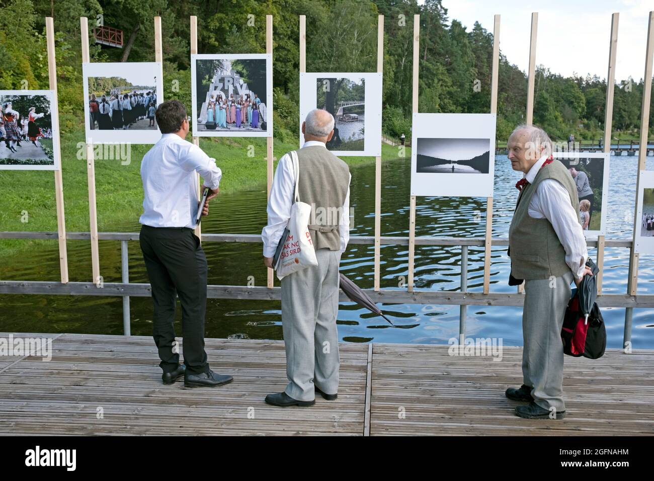 Drei Männer genießen eine Fotoausstellung im Freien auf dem Pier in Orge City, Orge City Festival, Lettland Stockfoto