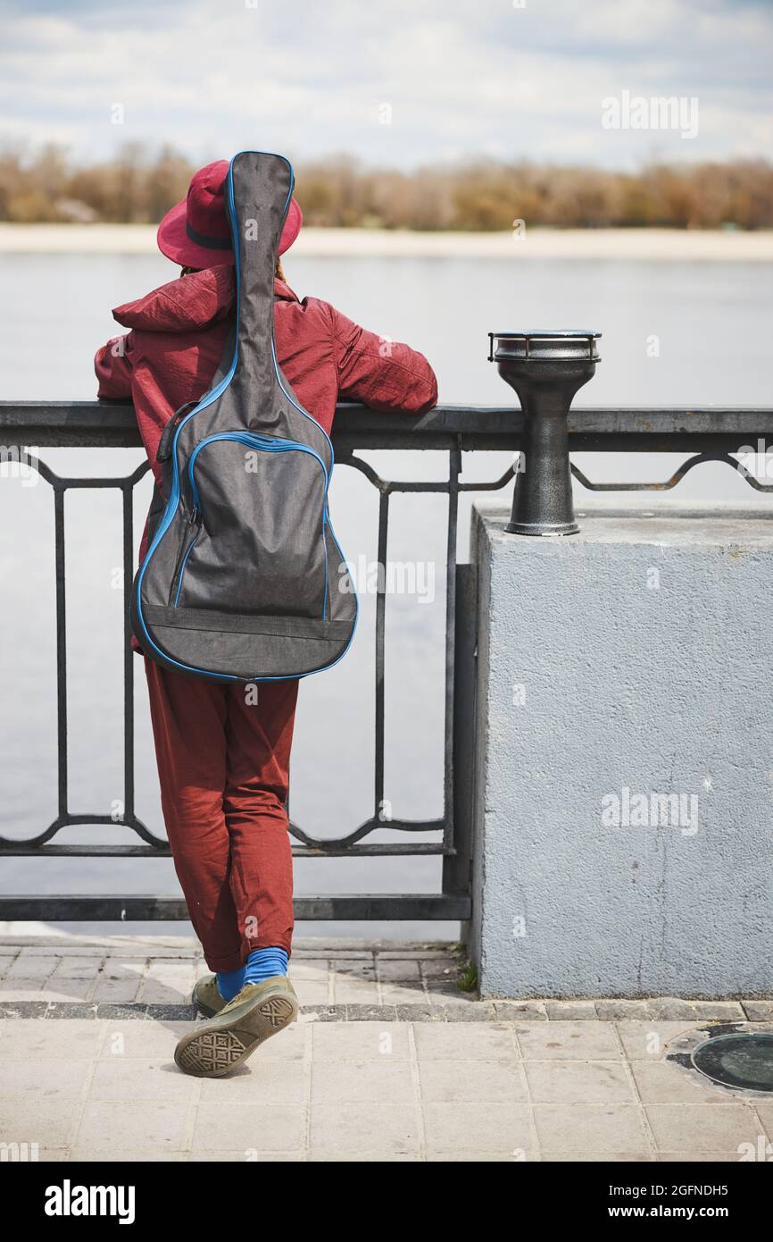 Verträumter Straßenmusiker, der auf den Fluss schaut Stockfoto