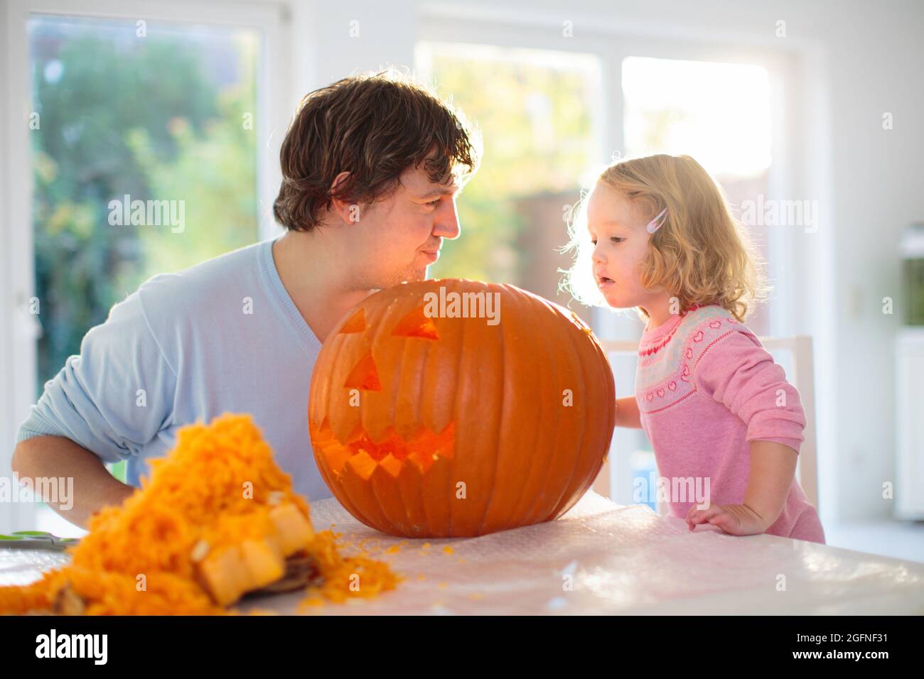Vater und Kind schnitzen Kürbis für Halloween. Papa und kleines Mädchen schnitzen Jack-o-Laterne für Trick or Treat und Hauseingang Dekoration. Eltern Stockfoto