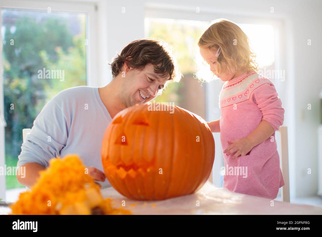 Vater und Kind schnitzen Kürbis für Halloween. Papa und kleines Mädchen schnitzen Jack-o-Laterne für Trick or Treat und Hauseingang Dekoration. Eltern Stockfoto