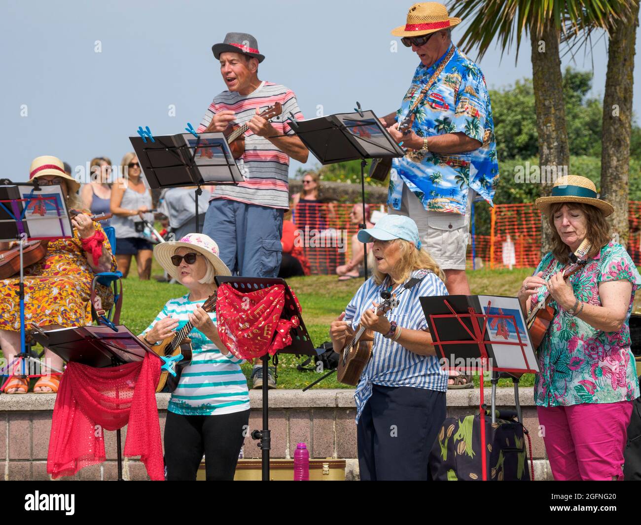 All@C, eine lokale Ukulele-Gruppe (eine Gruppe von Rentnern), die beim jährlichen Bude-Stratton Heritage Festival, Bude, Cornwall, Großbritannien, 25/07/2021, singt und spielt Stockfoto