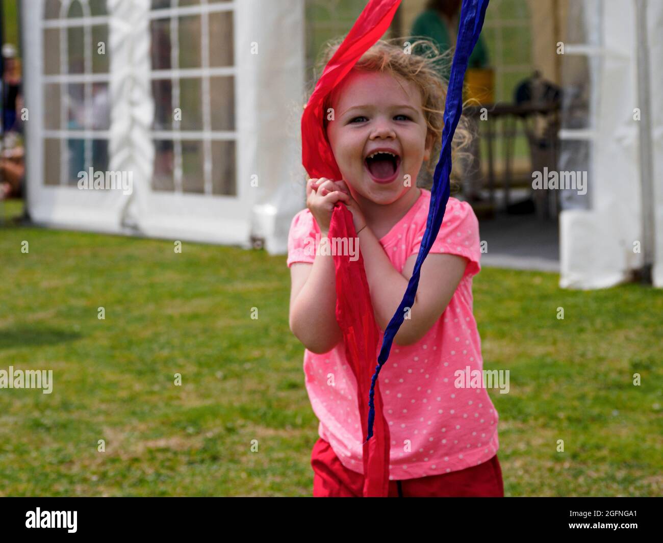 Kleines Kind, das beim Festival in Cornwall, Großbritannien, mit Fahnenbändern spielt Stockfoto