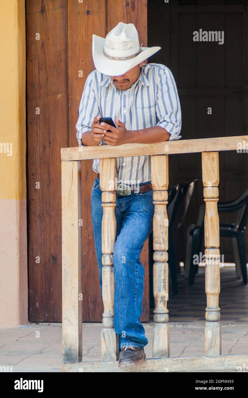 SAN MANUEL DE COLOHETE, HONDURAS - 15. APRIL 2016: Einheimischer Mann nutzt ein Handy. Stockfoto