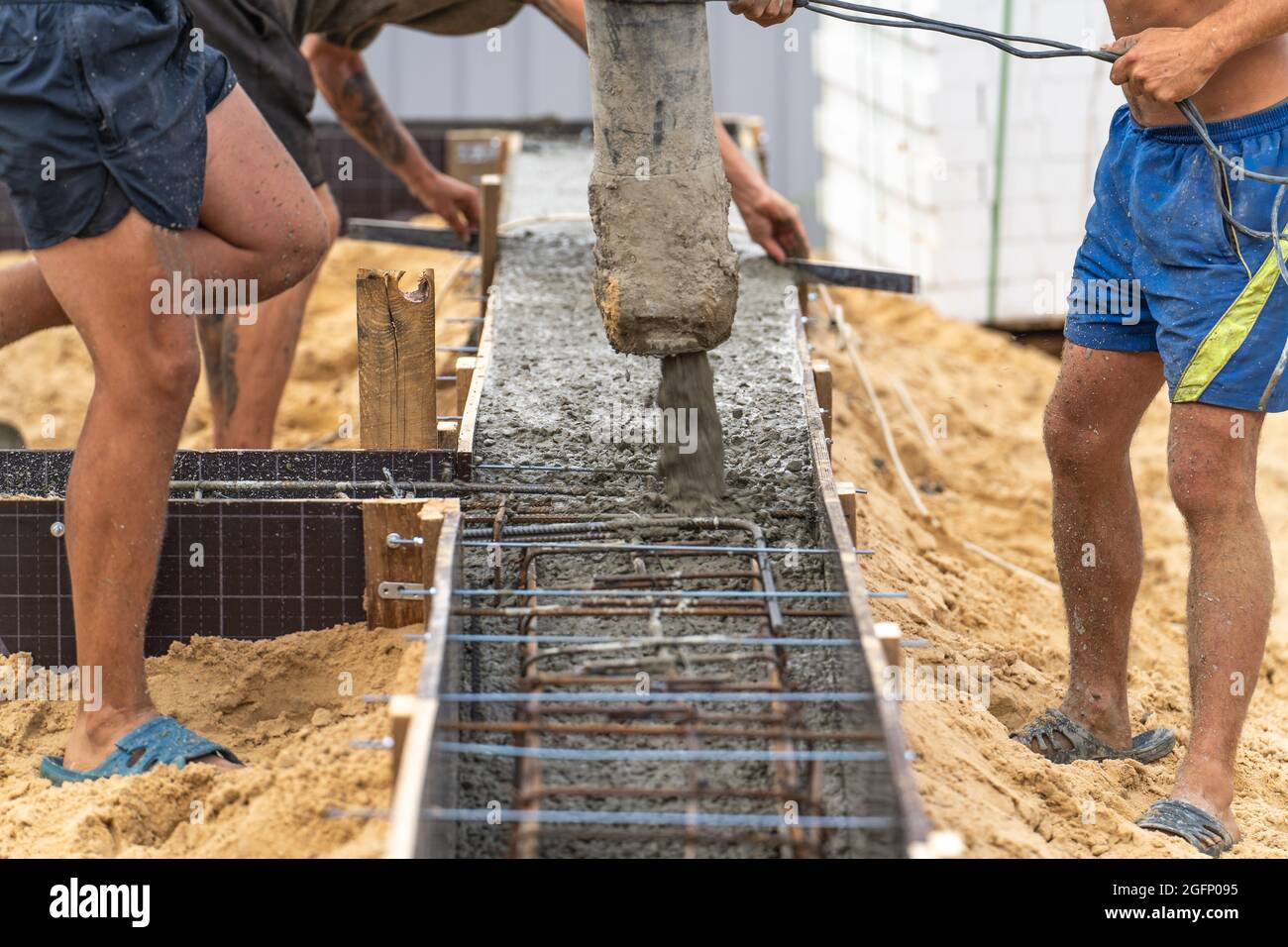 Gießen von Zement oder Beton mit automatischer Pumpe, Baustelle mit verstärktem Gitter-Fundament, Beginn des neuen Hausbaus. Stockfoto