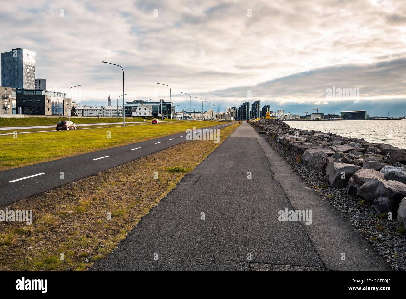 Uferpromenade, der an einem Sommerabend parallel zu einem Radweg und einer großen Stadtstraße verläuft Stockfoto