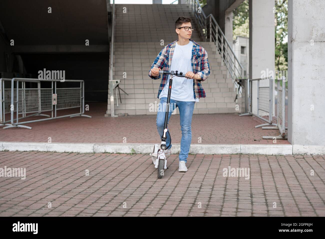 Ein attraktiver Kerl in einem karierten Hemd fährt einen Elektroroller. Stockfoto