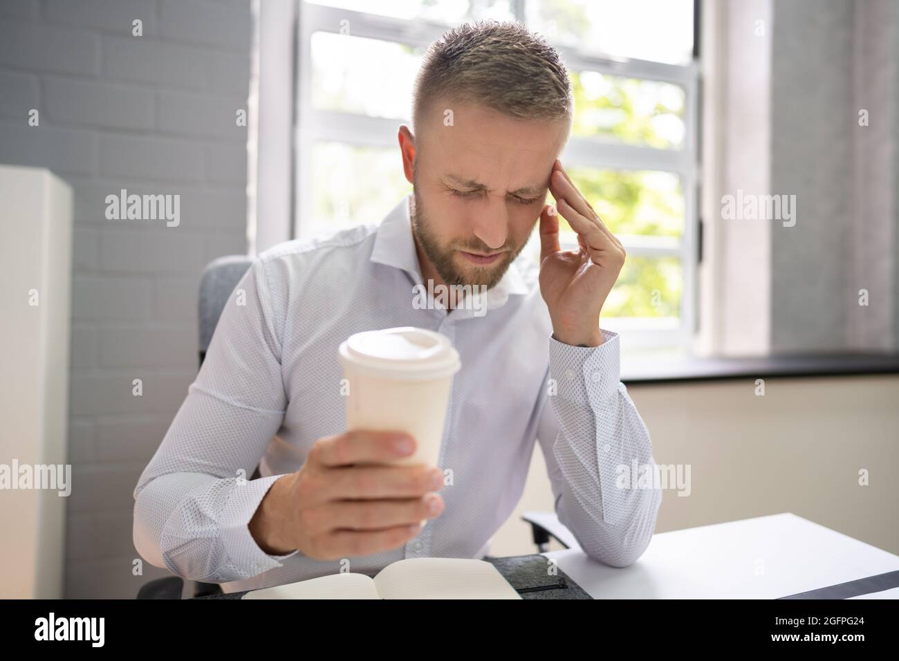 Person, Die Einen Kaffeebecher Hält, Hat Kopfschmerzen Und Migräne Stockfoto