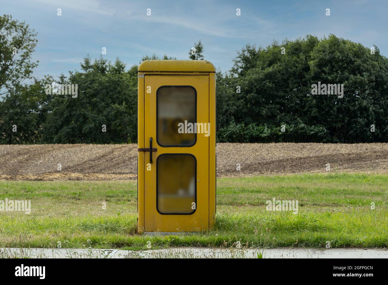 Alte gelbe Telefonzelle auf einer Wiese außerhalb der Stadt Stockfoto