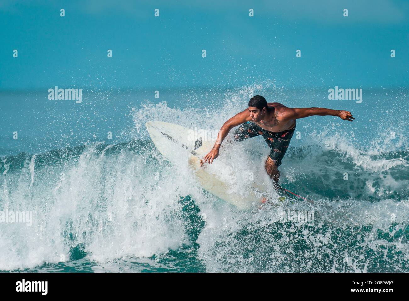 Playa Hermosa, Guanacaste, Costa Rica - 07.26.2020: Ein junger Mann aus der Region mit Tattoos, die ihre Fähigkeiten zeigen, indem er auf einer großen Welle an der Pazifikküste reitet Stockfoto