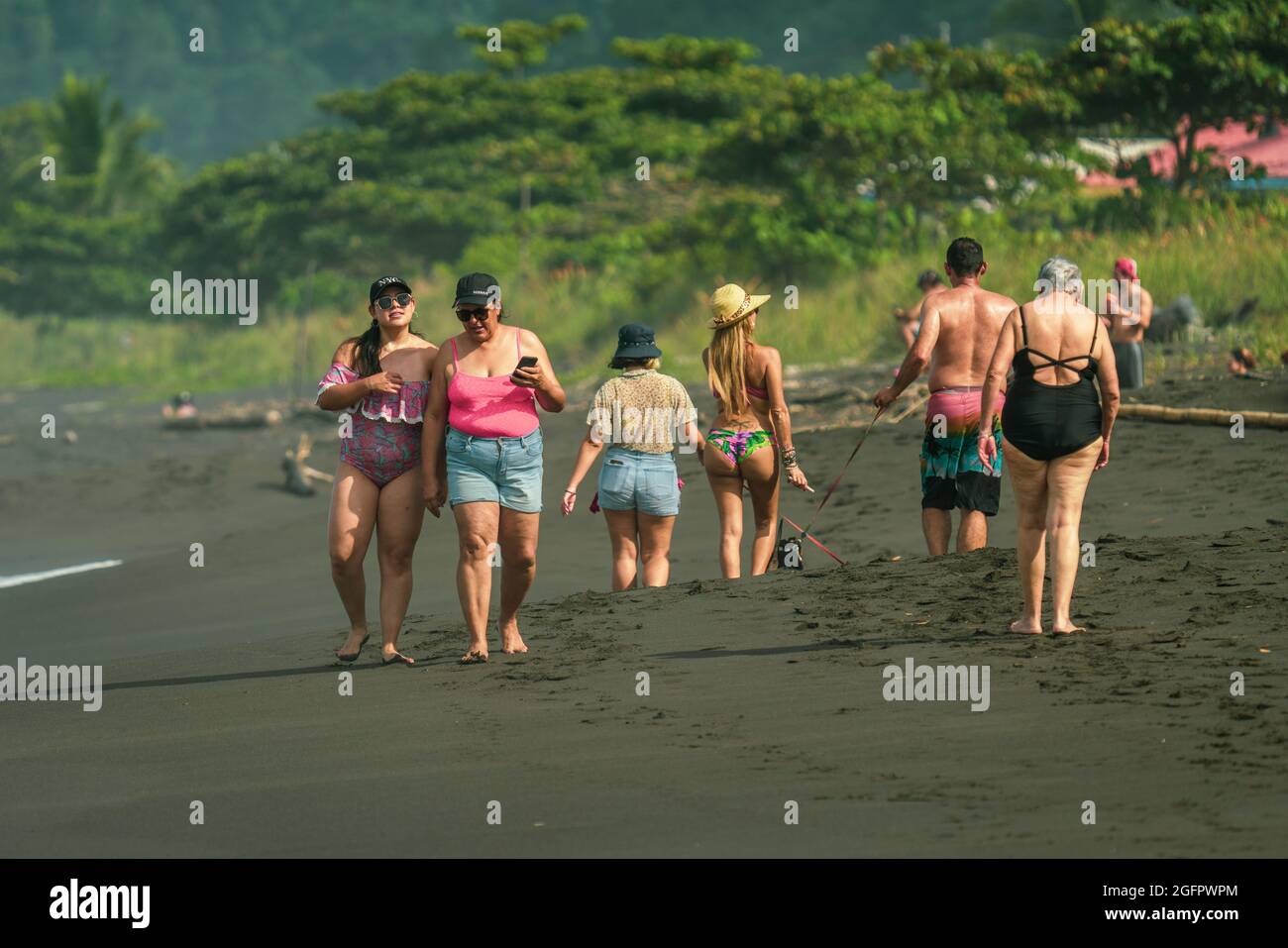 Menschen, die an einem wunderschönen, malerischen Strand mit vulkanischem Sand an der Pazifikküste von Costa Rica spazieren gehen Stockfoto