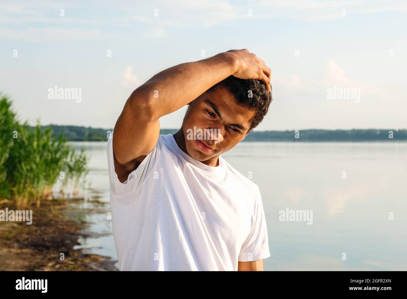 Afroamerikanischer Mann im weißen T-Shirt, der am Flussufer posiert Stockfoto