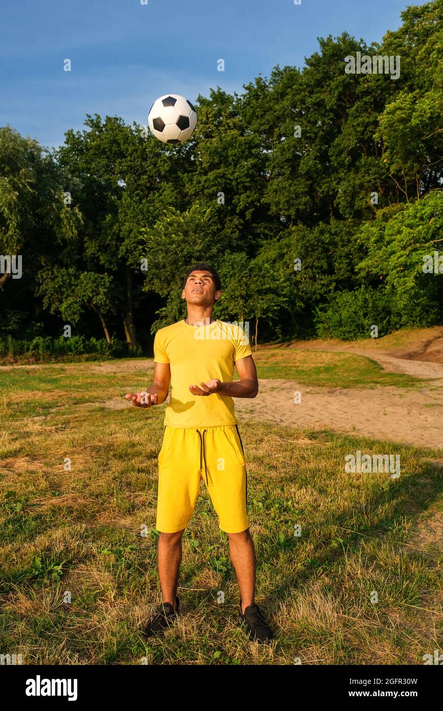 Man trainiert und verbessert die Ballkontrolle am grasbewachsenen sandigen Flussufer Stockfoto