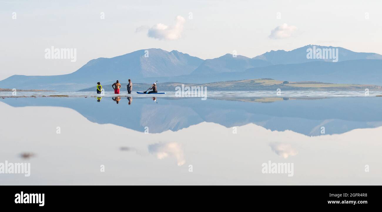 Ettrick Bay reflektiert Menschen, die paddeln und paddeln mit den Hügeln von Arran hinter und der Insel Inchmarnock, Isle of Bute, Schottland Stockfoto