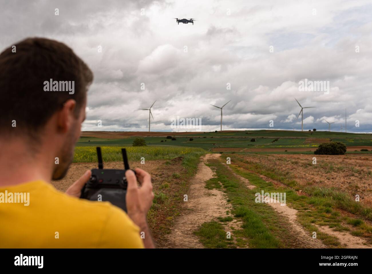 Zurück Ansicht eines nicht erkennbaren kaukasischen jungen Erwachsenen, der eine Drohne in EINEM nachhaltigen Windmühlenfeld fliegt. Lernkonzept. Stockfoto