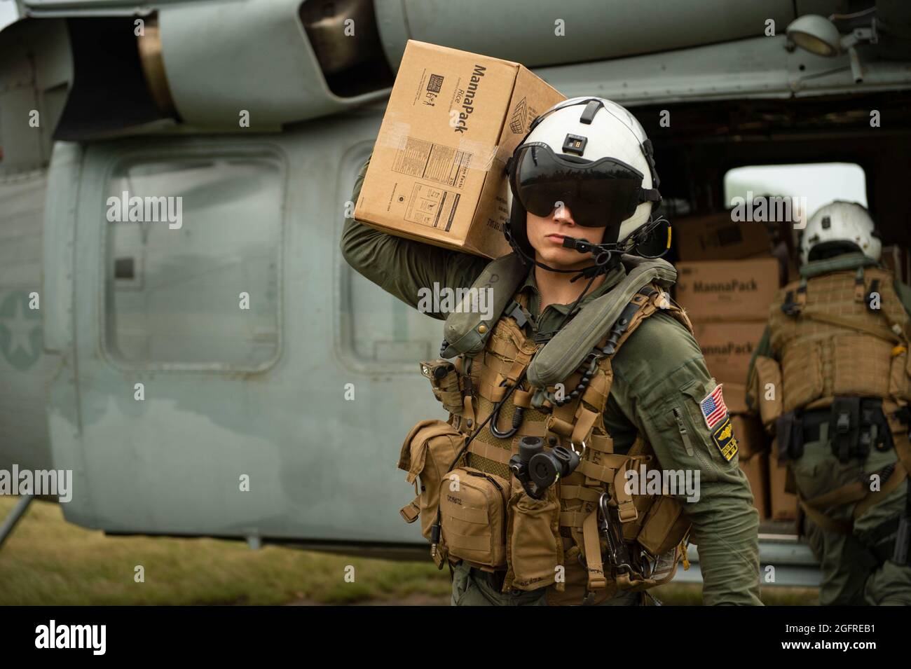 210825-N-MD802-1299 ANSE-A-VEAU, Haiti - (Aug 25, 2021) – Hospital Corpsman 3rd Class Jace Borowiak, der den „Chargers“ des Helicopter Sea Combat Squadron (HSC) 26 zugewiesen wurde, trägt während einer humanitären Hilfsmission zur Unterstützung der US Agency for International Development (USAID) am 25. August 2021 eine Kiste mit Lebensmitteln aus einem Sea Hawk-Hubschrauber der MH-60S. HSC-26 ist an das Amphibientransportschiff USS Arlington (LPD 24) der San Antonio-Klasse angeschlossen. Arlington wird bei den U.S. Naval Forces Southern Command/U.S. eingesetzt 4. Flotte zur Unterstützung der humanitären Hilfe und der Katastrophenhilfe (HADR) in Haiti Stockfoto