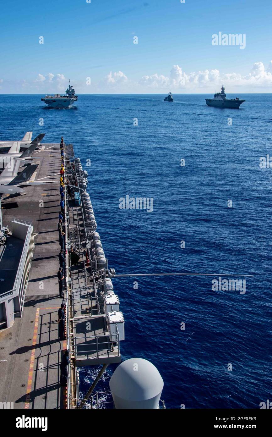 PHILIPPINISCHES MEER (Aug 24, 2021) Seeleute, die dem nach vorne eingesetzten amphibischen Sturmschiff USS America (LHA 6) zugewiesen wurden, ehren den Hubschrauber-Zerstörer JS Ise (DDH 182) rechts der Japan Maritime Self-Defense Force und den Zerstörer JS Asahi (DD 119), während er vor dem Royal Navy-Flugzeugträger HMS Queen Elizabeth (R 08) dampft. Amerika, das Flaggschiff der America Expeditionary Strike Group, ist zusammen mit der 31. MEU im Verantwortungsbereich der 7. US-Flotte tätig, um die Interoperabilität mit Verbündeten und Partnern zu verbessern und als einsatzbereite Einsatztruppe für Frieden und Stabilität in zu dienen Stockfoto