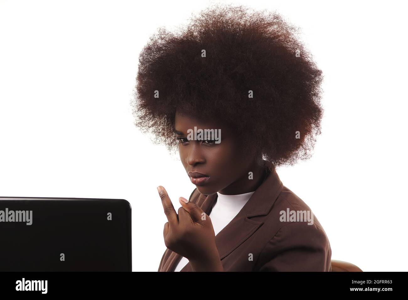 Junge, schwarze, lateinamerikanische Geschäftsführerin aus Latina, mit afro-Haaren, mit wütender Geste, die auf ihren Laptop schaut, auf weißem Hintergrund Stockfoto