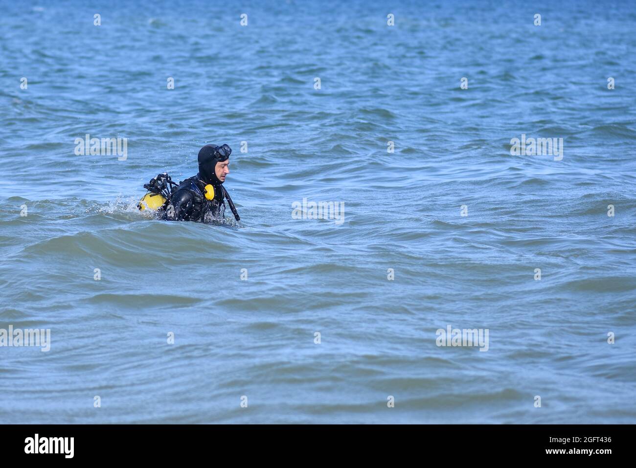 Ein Mann in einem Tauchanzug tritt ins Wasser. Redaktionell Stockfoto