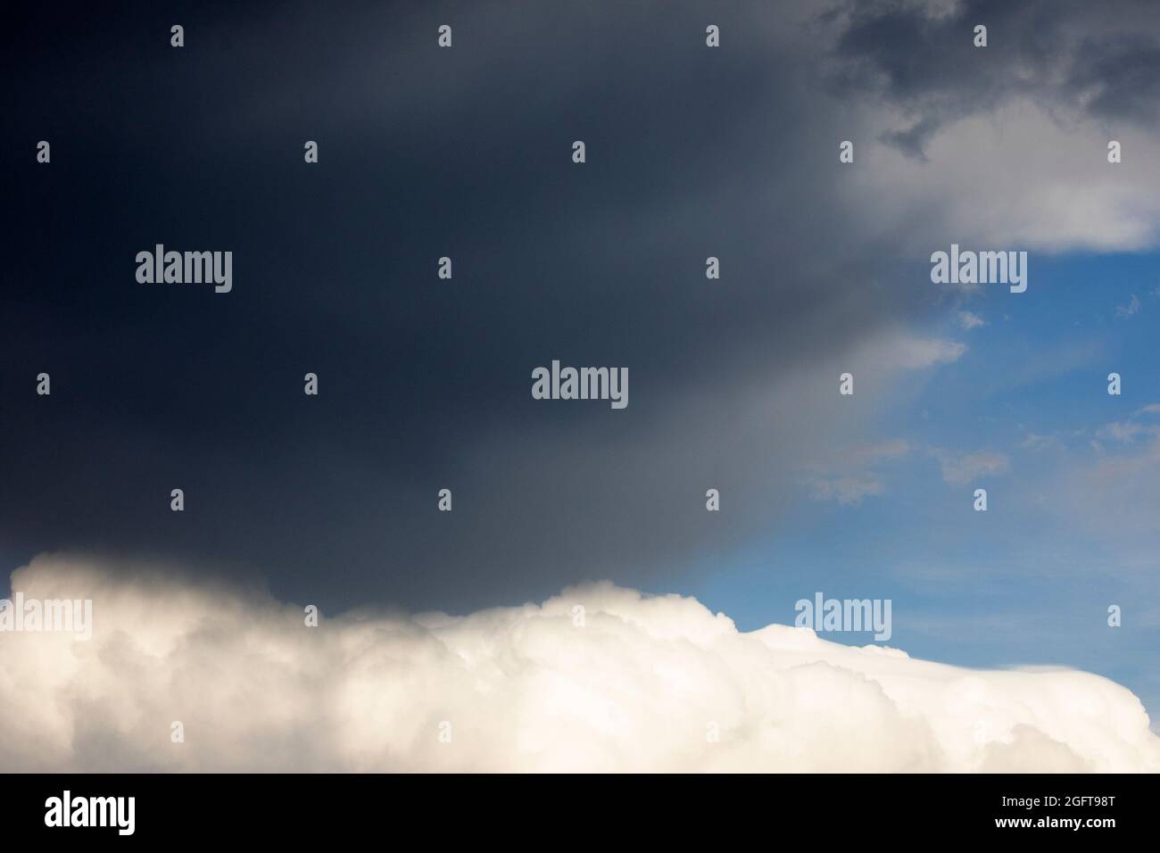 Dunkelgraue Sturmwolken, die sich an sonnigen Tagen über der weißen Cumuluswolke bewegen Stockfoto