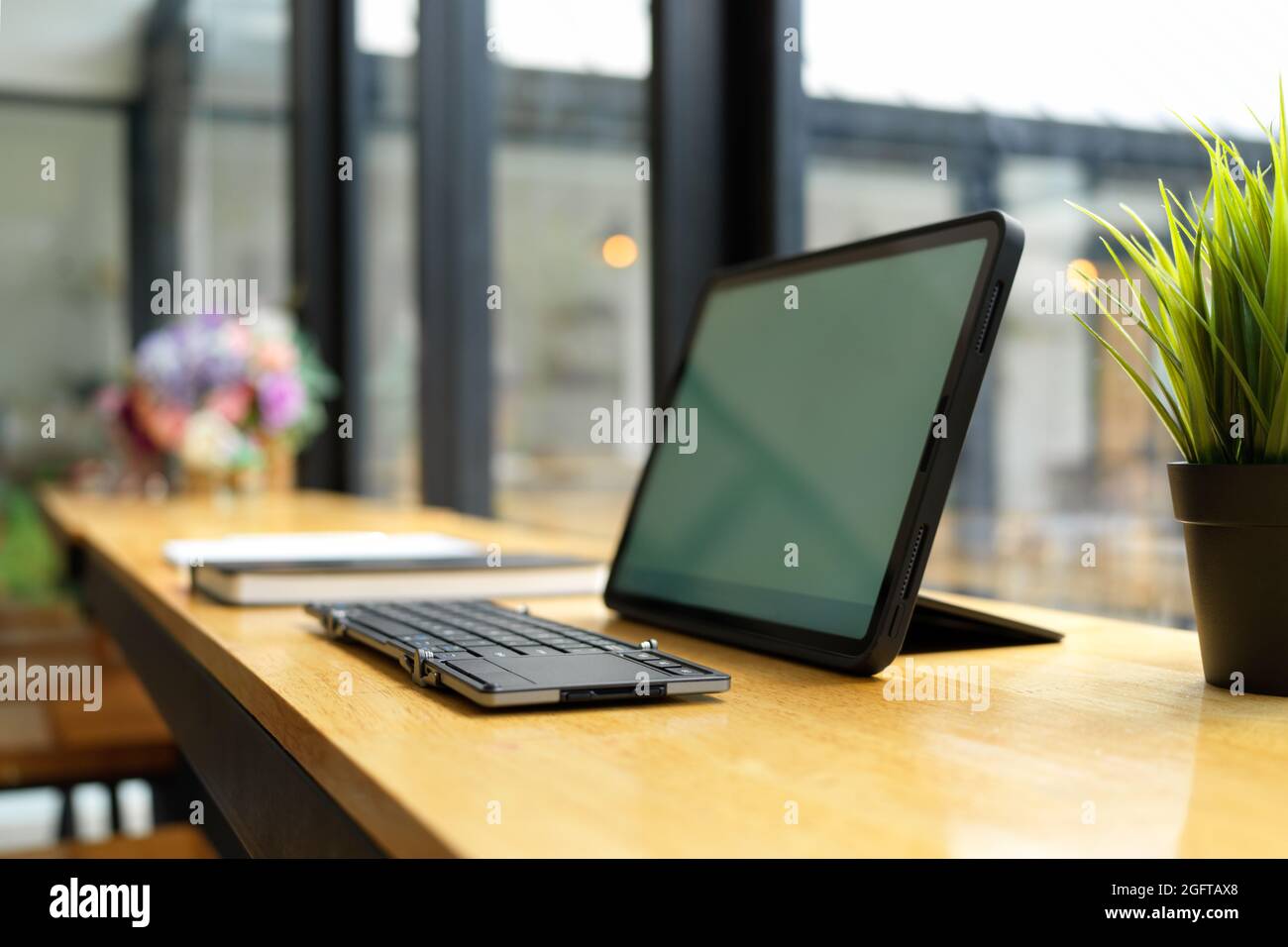 Seitenansicht, tragbares Tablet mit magischer Tastatur auf Holztisch im Café, Konzept für drahtlose Geräte Stockfoto